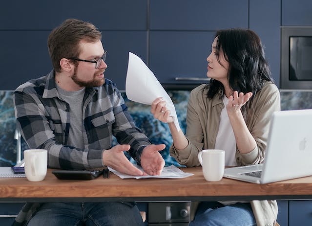 stressed couple sitting at table with paper